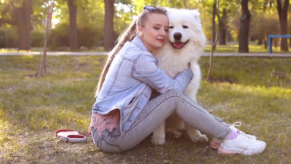 The Girl Lies on the Grass with Her Dog Hugs