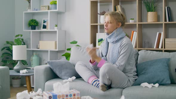 Girl Blows Her Nose in a Napkin on Sofa