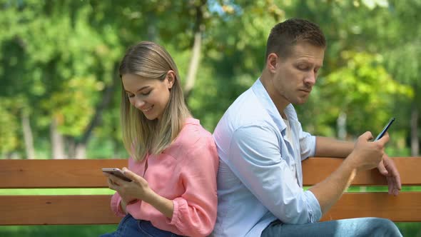 Boyfriend and Girlfriend Sitting Back-To-Back With Phones Guy Is Jealous of Girl