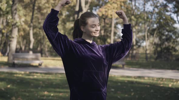 Portrait of Smiling Young Sportswoman Showing Strength Gesture and Looking at Camera