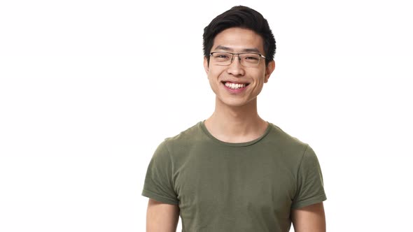 Portrait of Pleased Asian Man Wearing Eyeglasses and Basic Tshirt Grinning with Bright Smile
