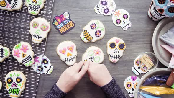 Step by step. Flat lay. Decorating sugar skull cookies with different color royal icing.