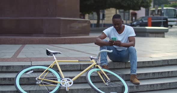 Handsome African American Young Man Using His Smartphone, Checking News, Looking Serious While