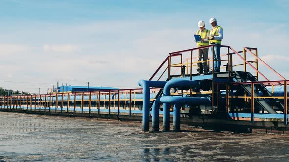 Wastewater Treatment Site with Male Workers Talking. Wastewater Treatment Concept.