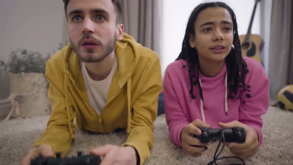 Camera Zooming in and Moving Up Showing Two Cheerful Friends Using Gaming Console, Giving High Five