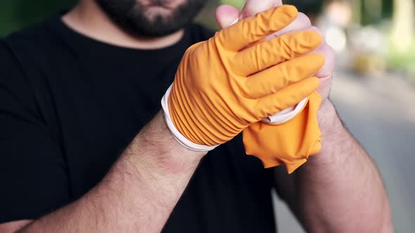 Man Is Taking Off Rubber Gloves After Finishing Volunteer Work at a Local Park