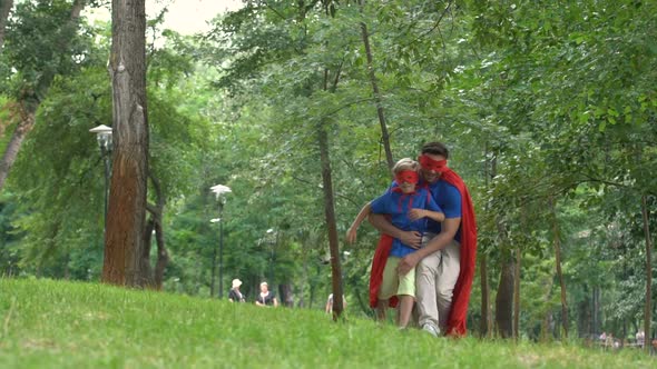 Son and Father Dressed in Superheroes, Playing Together in Park, Happy Weekend