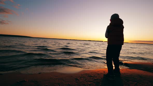 A Boy Is Reeling Up a Fishing Rod While Standing on Shore