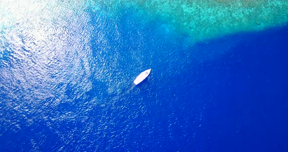 Beautiful birds eye tourism shot of a white sandy paradise beach and blue ocean background in vibran