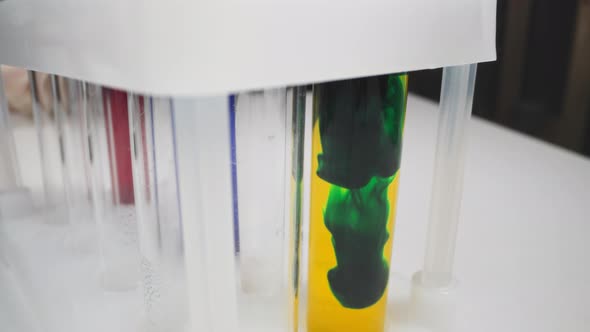 Flow of Dark Green Paint Settles Down in Test Tube Macro