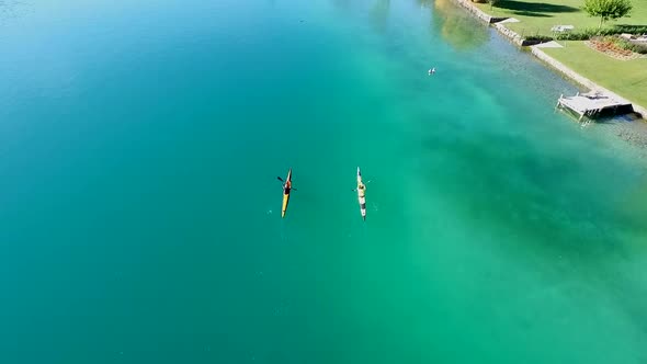 Two kayakers paddle in a scenic mountain lake