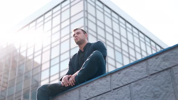 Low Angle Shot Handsome Man Sits on Parapet Against Building