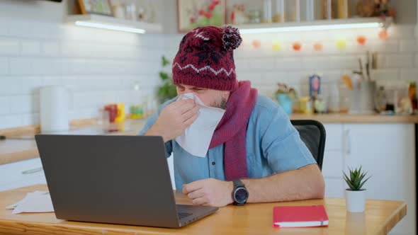 Sick Bearded Man Blows His Nose Into a Paper Napkin While Working Remotely at Home