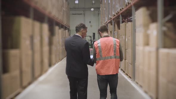 Worker and businessman with digital tablet in warehouse