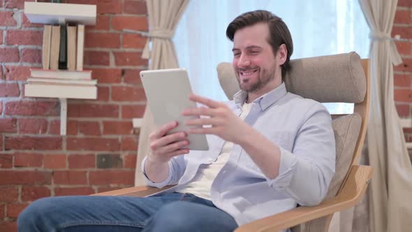 Casual Young Man Talking on Video Call on Tablet on Sofa
