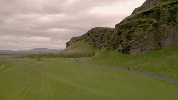 Aerial drone view over people, walking towards the Gljufrabui waterfall, in cloudy Iceland