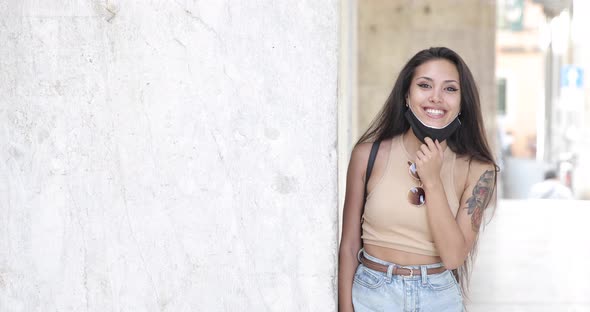 Smiling woman wearing face mask, leaning on wall