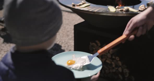 Father cooking breakfast for son. Fried eggs, cabbage, mushroom grilled on bbq grill.