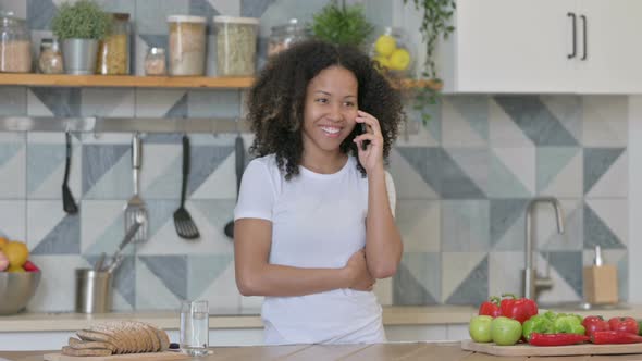 African Woman Talking on Smartphone While Standing in Kitchen