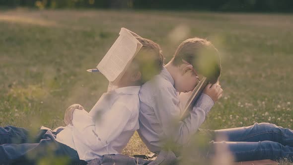 Young Boy Holds Book on Face Sitting Near Schoolmate