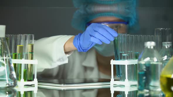 Scientist Checking Reaction in Tube and Adding Data to Tablet, Modern Equipment