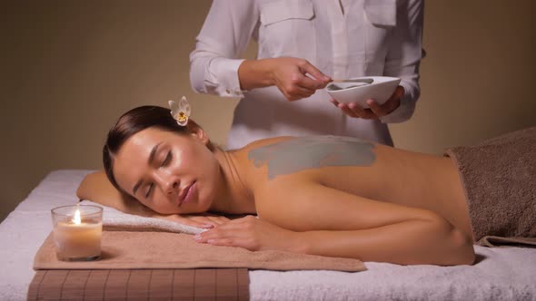 Woman and Cosmetologist Applying Clay Mask in Spa