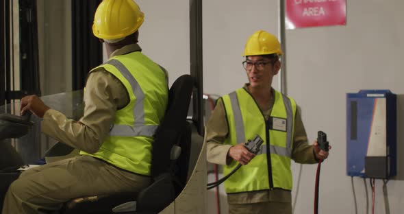 Diverse male workers wearing safety suits and sitting in turret truck in warehouse