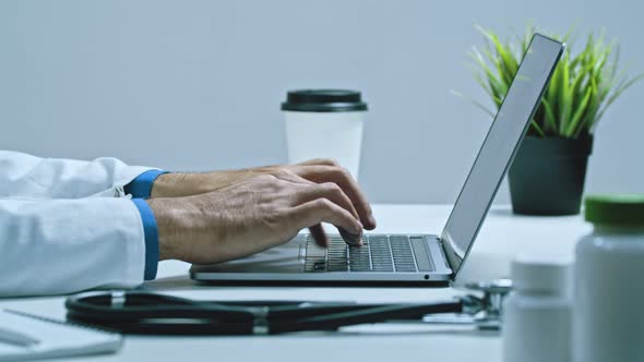 Male Doctor Working on Computer at Desk