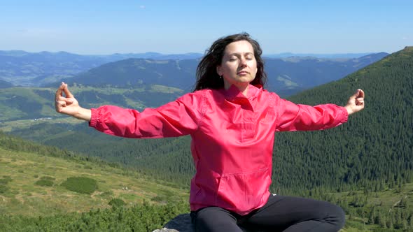 The girl sits on the top of the mountain and meditates. Relax in nature. Happiness and tranquility