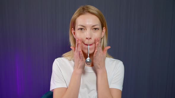 A Beautiful Woman Does Anti -Aging Exercises. Facial Gymnastics with a Handy Help Teaspoon. Face