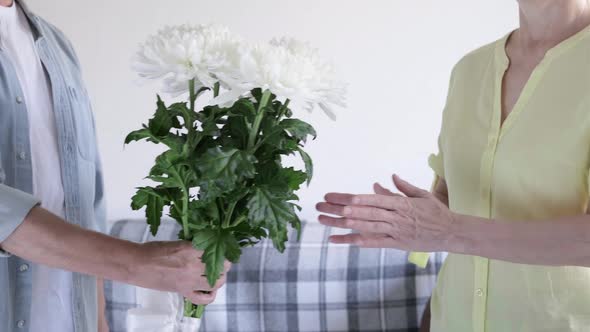 A Man Gives a Woman a Bouquet of White Chrysanthemums