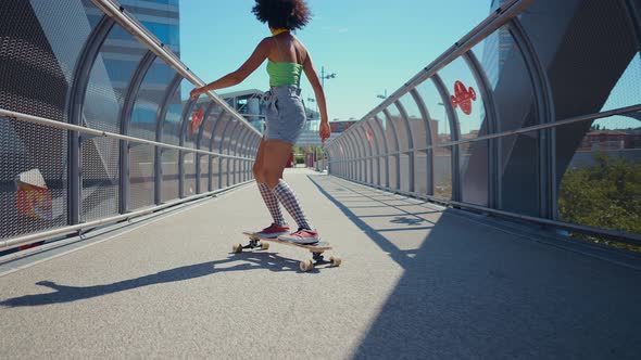 Beautiful young woman cruising around the city with her longboard.