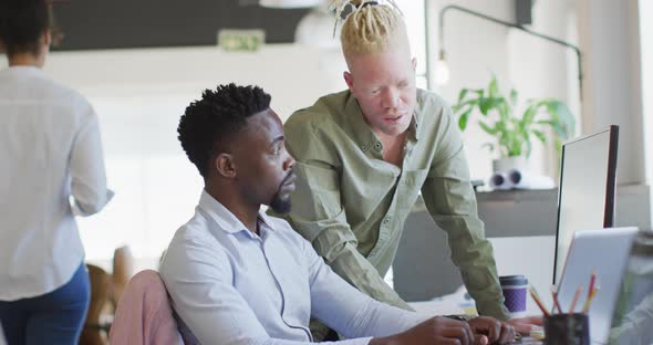 Diverse business people discussing with laptop in creative office