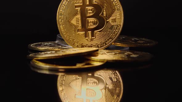 Bitcoin cryptocurrency gold coin stands among a pile of coins. Beautiful glare of light