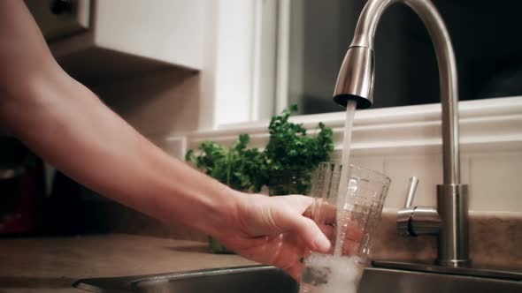 Man Filling a Glass of Water Before to go to Bed