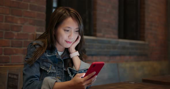 Woman use of mobile phone in coffee shop at night