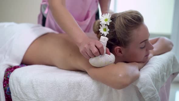 Massage Therapist Using Herbal Compress on Woman