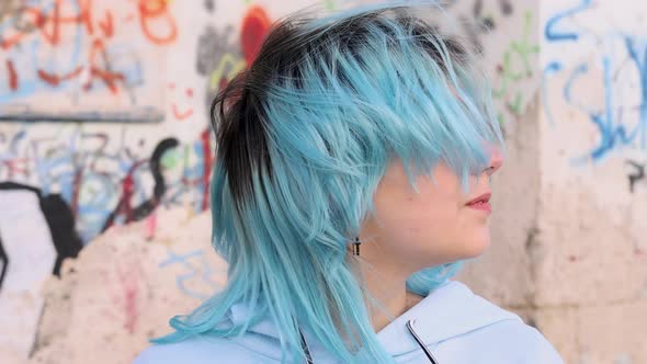 Blue haired teenage girl in hoodie turning head from right to left. Head portrait