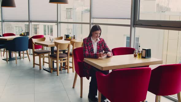 Young Woman Is Using Cellphone In Cafe