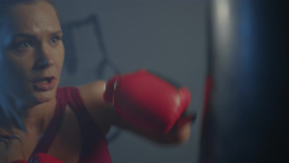 A female boxer trains on a punching bag in the gym