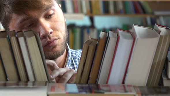 Young Man Browsing Through the Racks of Books in a Library