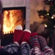 Couple feet in christmas woolen socks near fireplace with decorated tree in backg - VideoHive Item for Sale