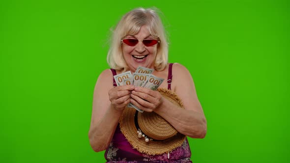 Senior Woman Traveler Tourist Takes Money From Hat Counting Bunch of Dollars Cash for Summer Trip
