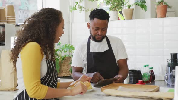 Portrait of happy african american male cafe owner and biracial female barista using tablet