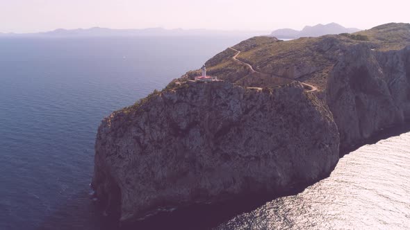 Lighthouse on rocky seashore with curved road