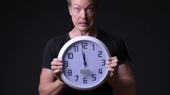 Young Handsome Man Holding Wall Clock Against Black Background