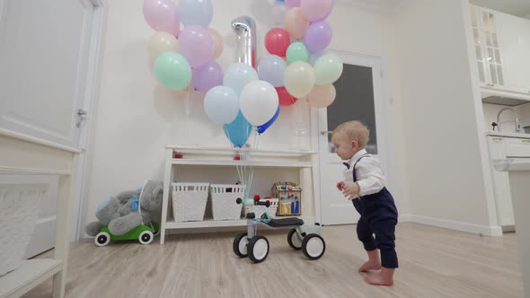 Kid on Baby Bicycle Balance Bike for Toddlers with Colorful Balloons 1 Year Old Baby Boy Celebrating