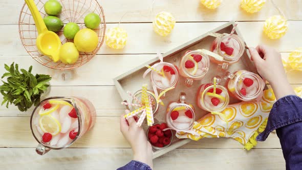 Raspberry lemonade garnished with fresh lemon and raspberries in drinking mason jars.