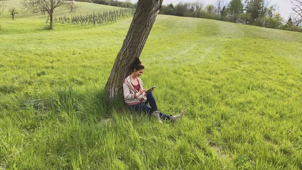 Woman using tablet, sitting on meadow