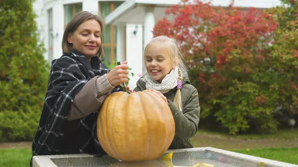 Mother and Daughter Carving Pumpkin Jack-O-Lantern, Having Fun Together, Weekend